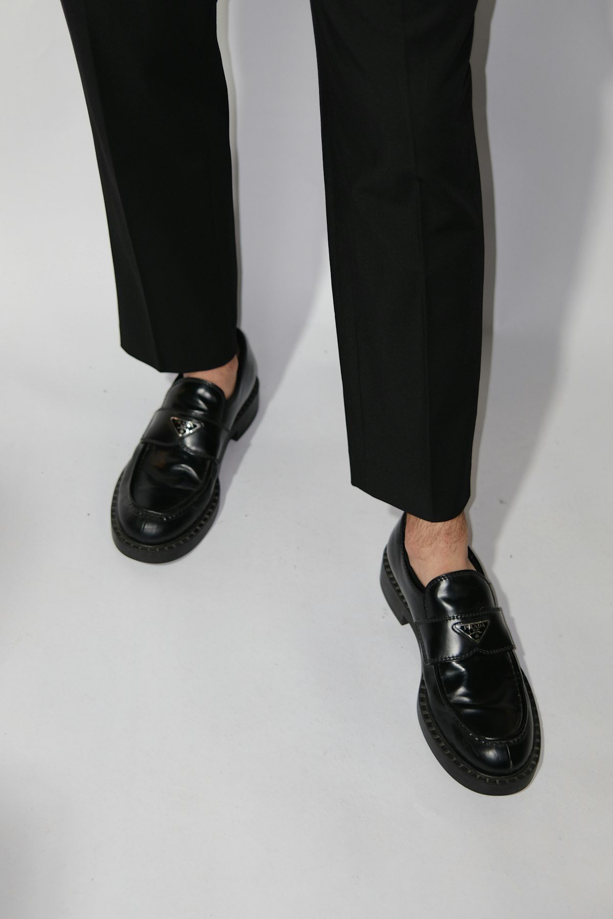 Black leather loafers worn with cropped dark trousers