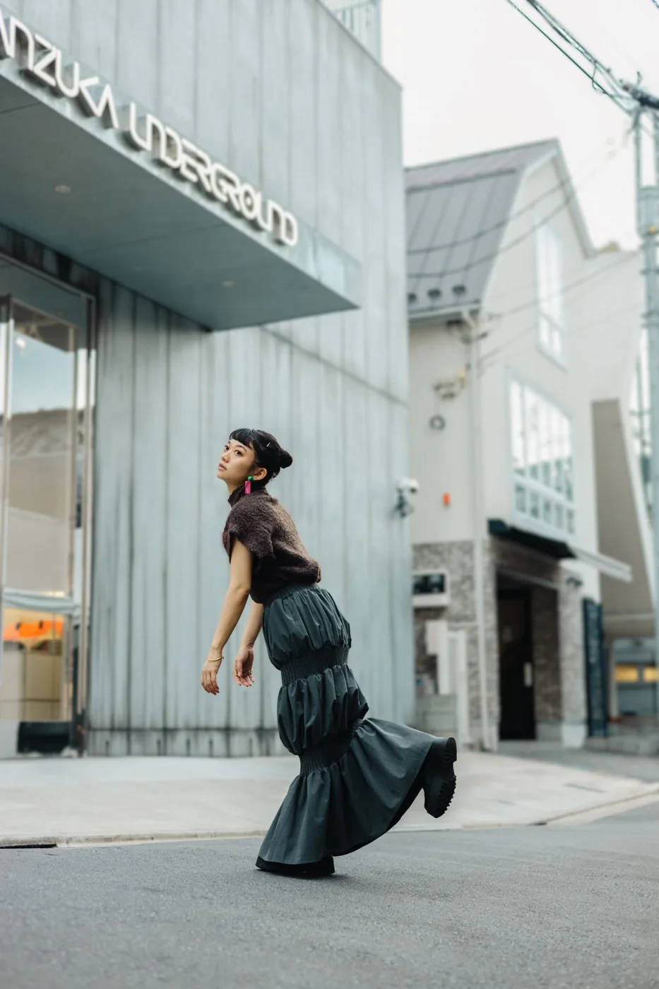 Woman in a plaid midi skirt posing on a city street