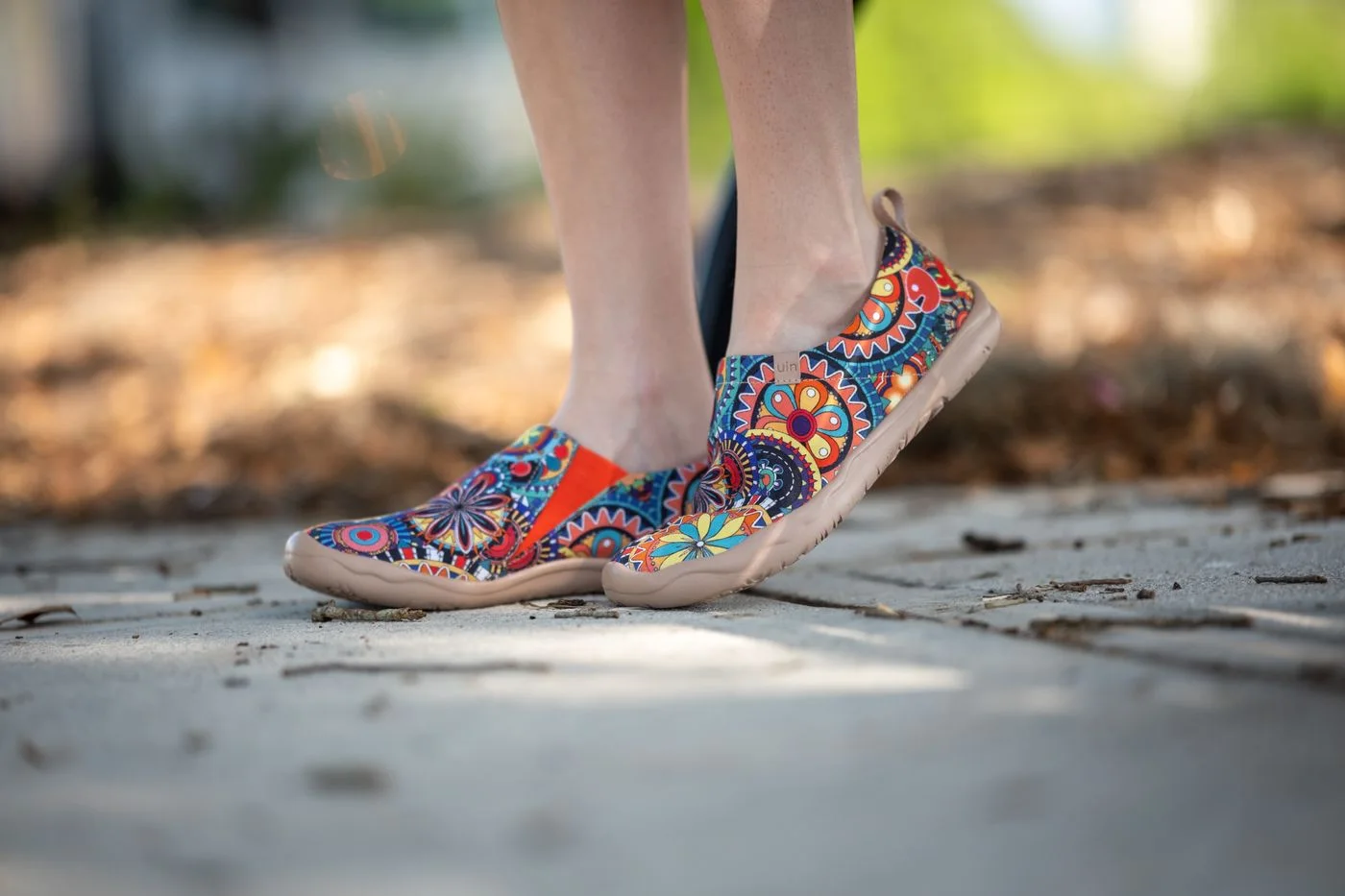 Colourful patterned lace-up shoes above a sunlit pavement.