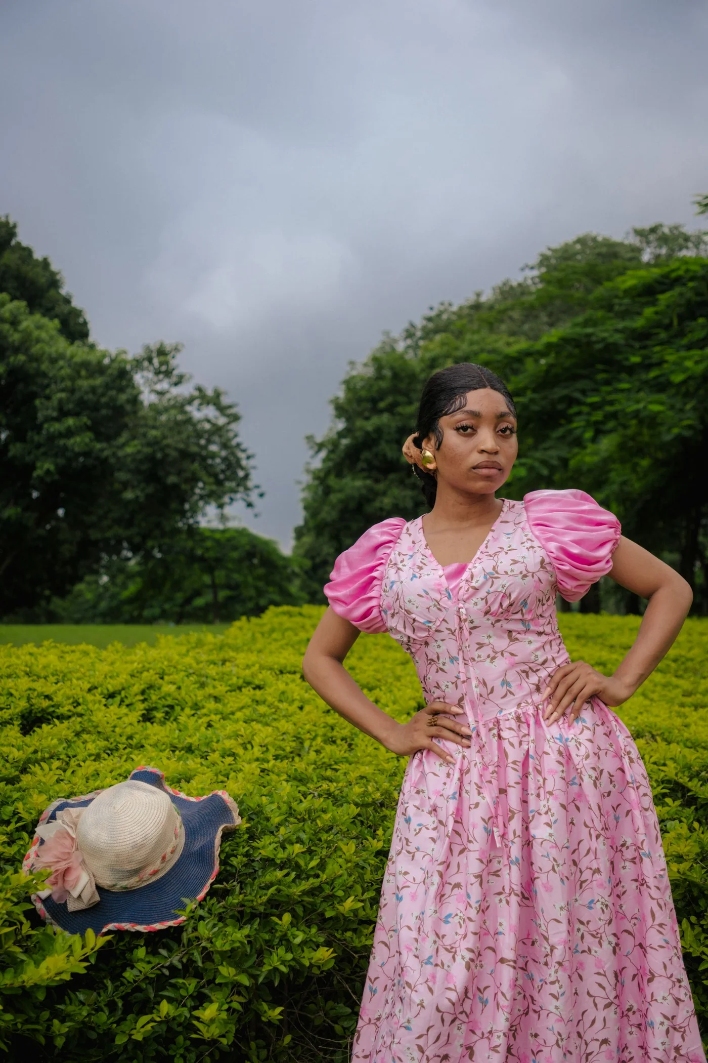 A woman in a pink floral dress in a garden.