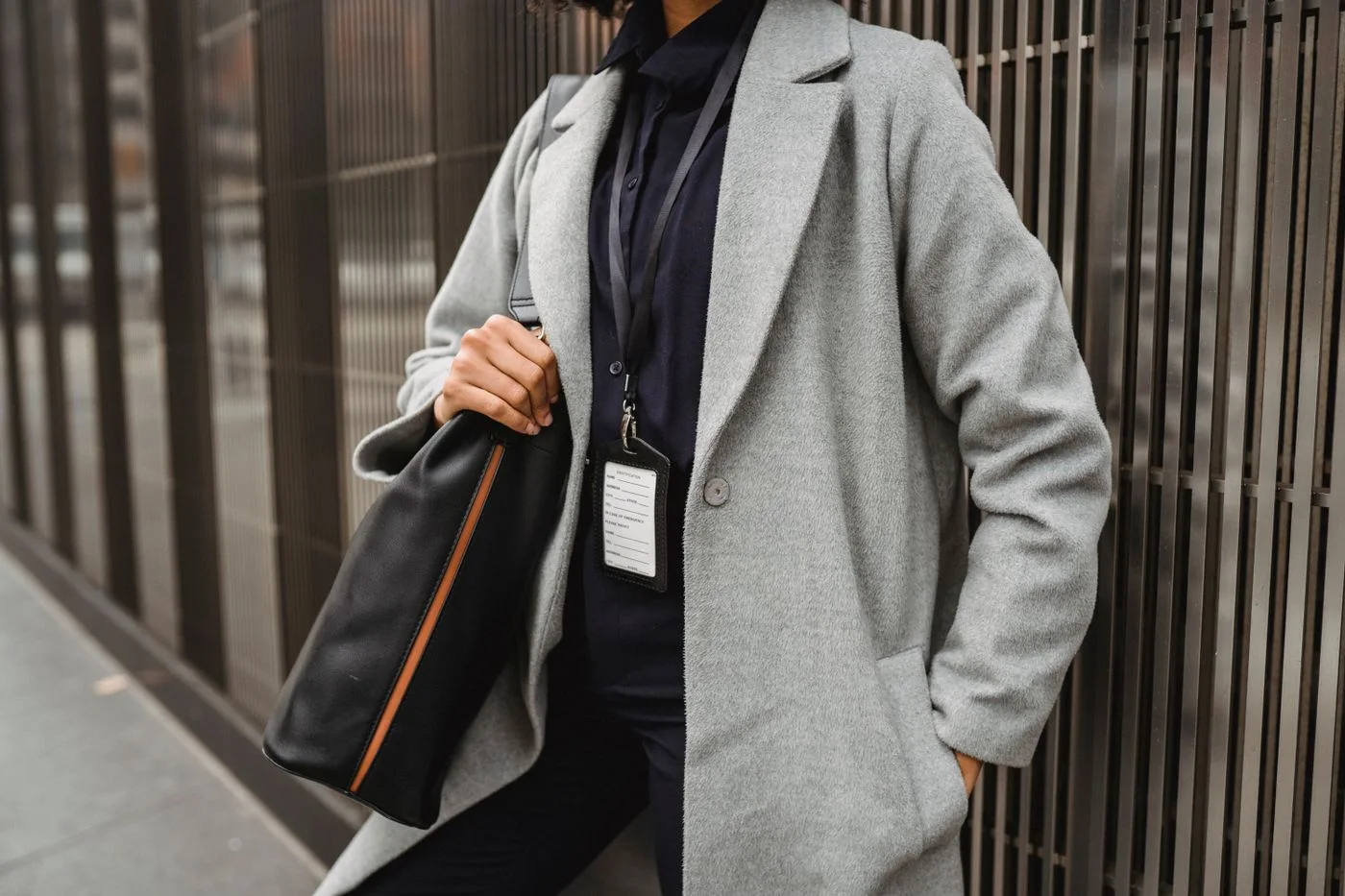 A person in a pale grey coat carrying a dark shoulder bag.