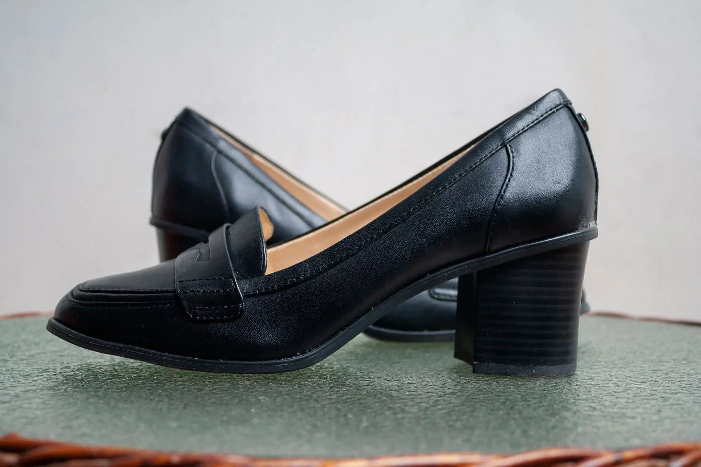 Dark slip-on shoes with low block heels on a pale surface.