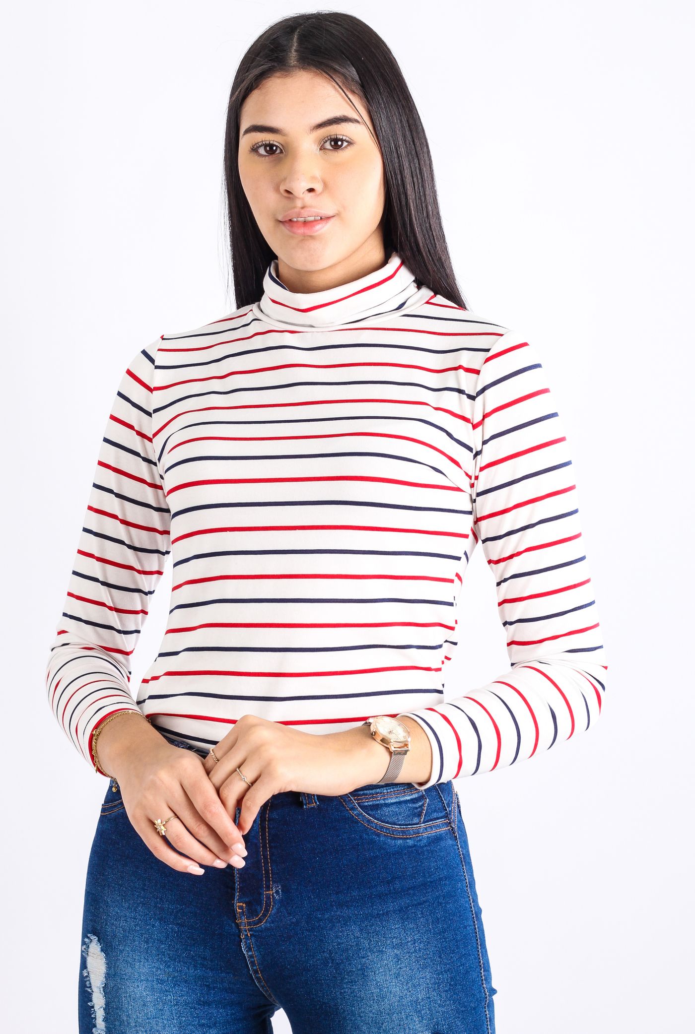 A woman in a striped high-neck top and jeans against a pale background.