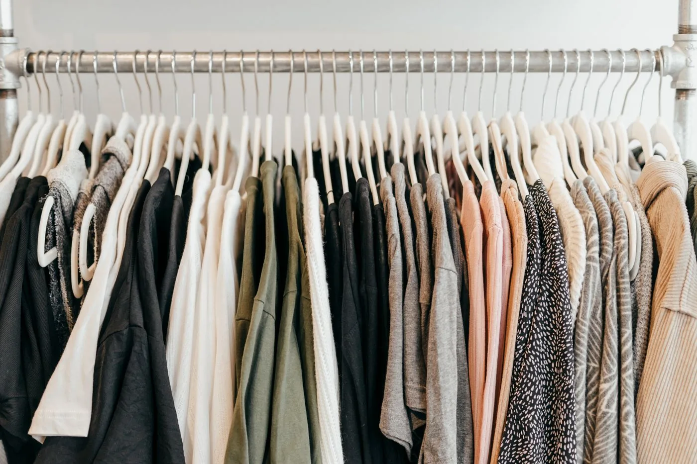 Pale and dark garments arranged on hangers along a long rail.