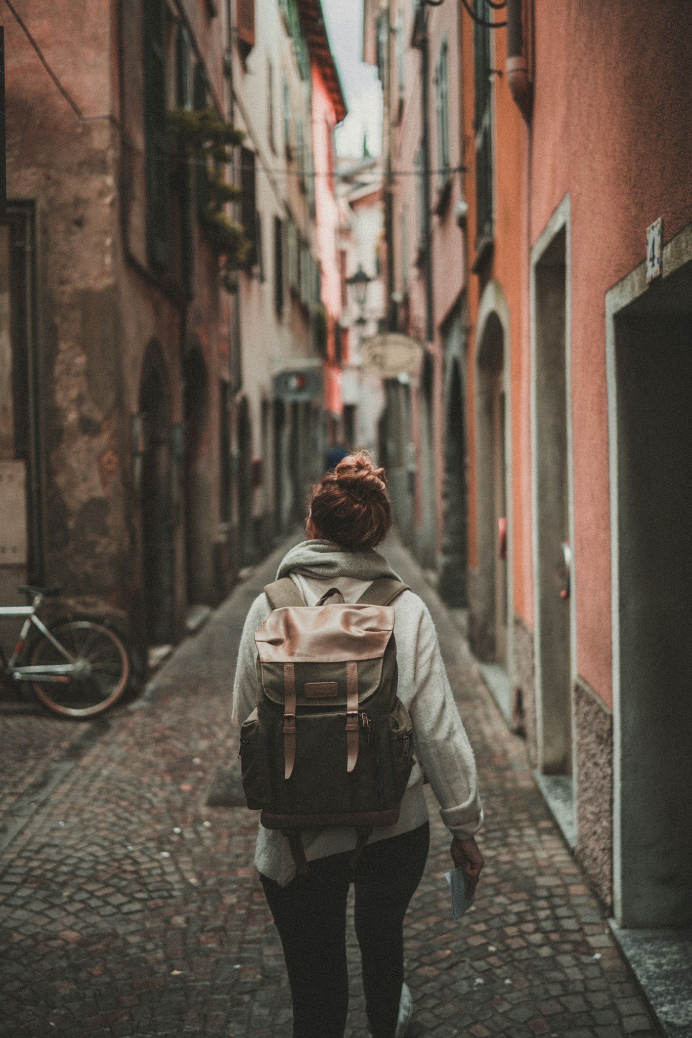 A traveller with a backpack in a narrow street between buildings.