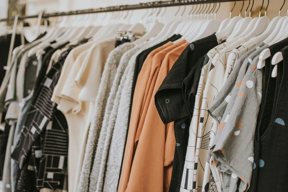 Pale, dark and warm-coloured garments arranged closely on a clothes rail.