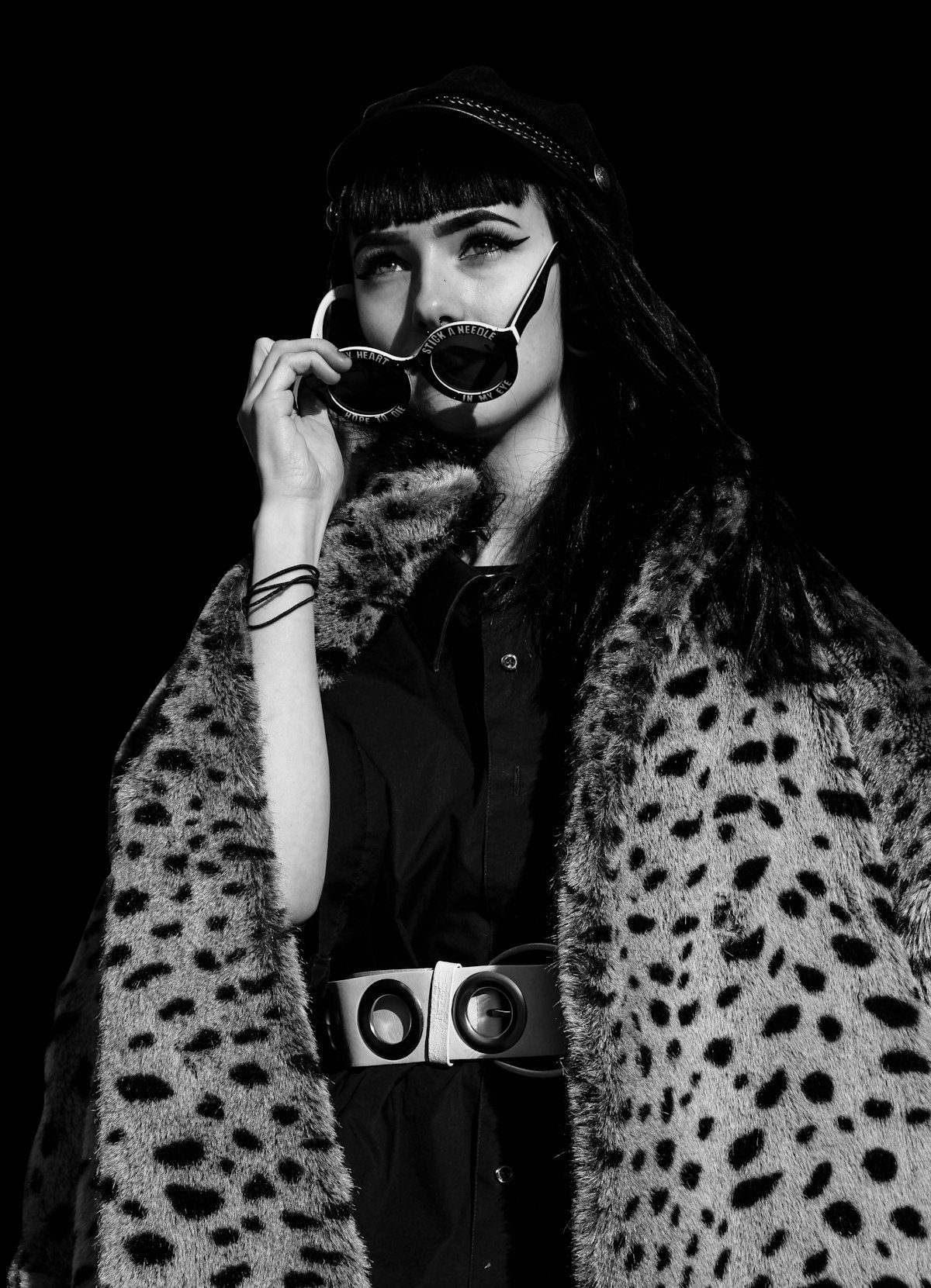 A monochrome photograph of a woman in an animal-print outer layer and dark hat.