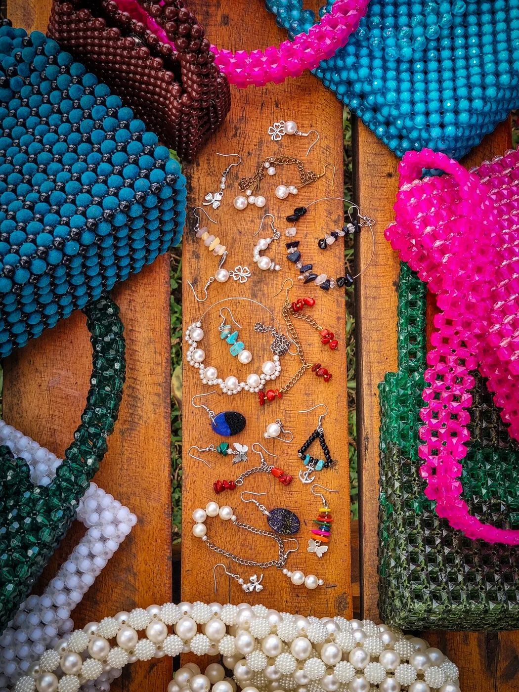 Brightly coloured beaded bags and jewellery arranged on a wooden surface.