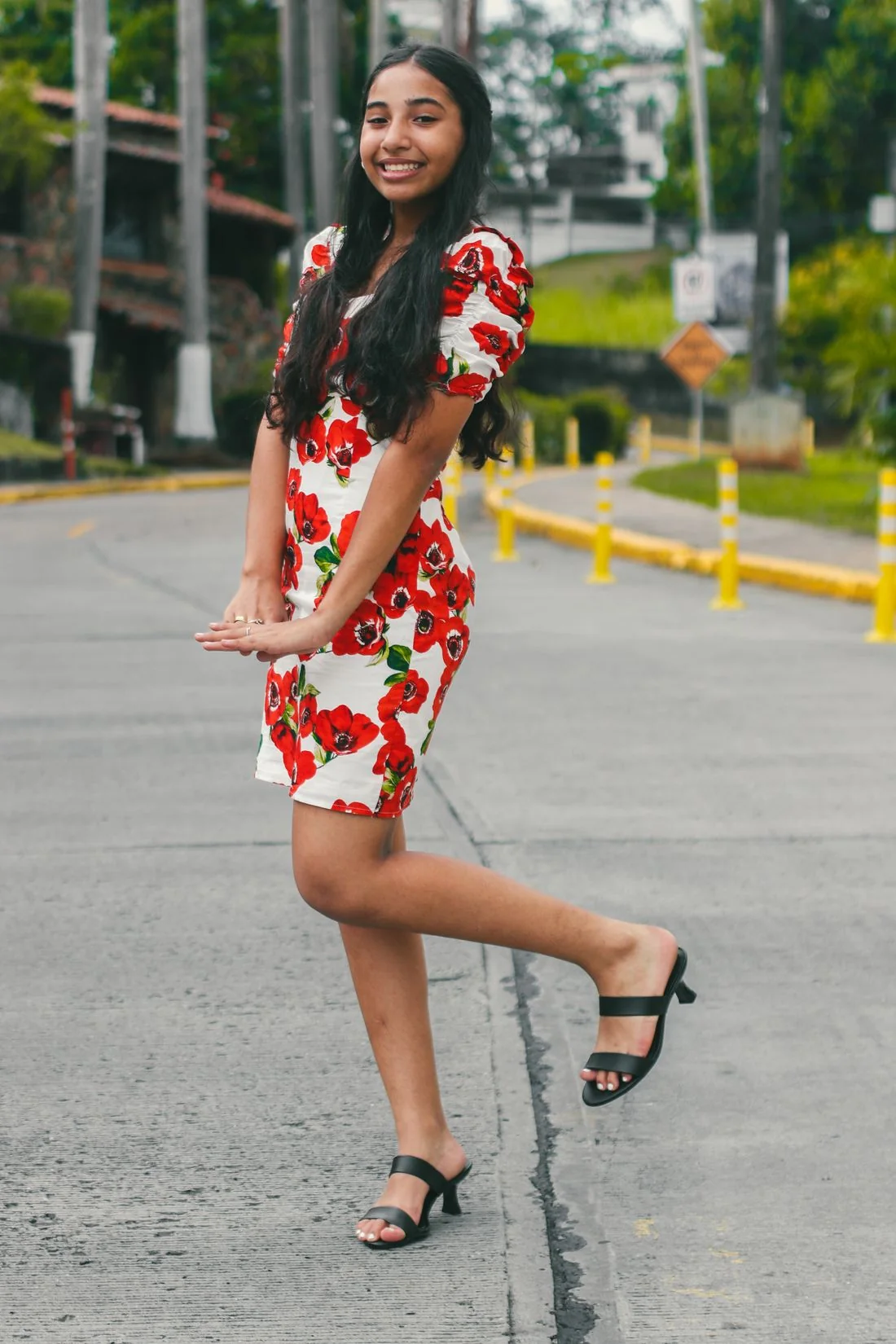 A woman in a floral dress on a city pavement.