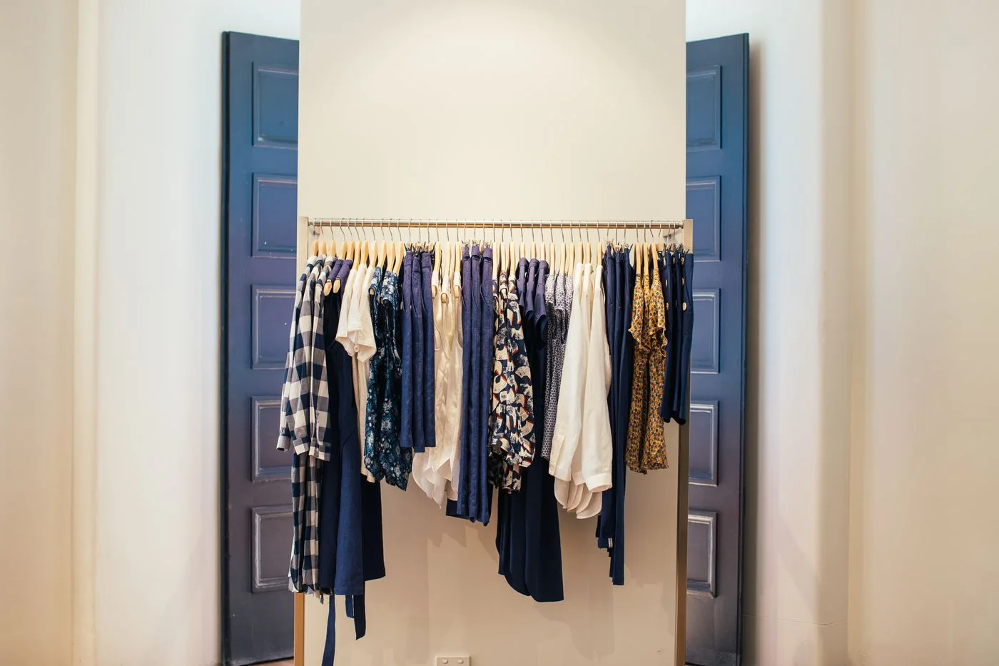 Garments hanging on a rail between two pale doors.