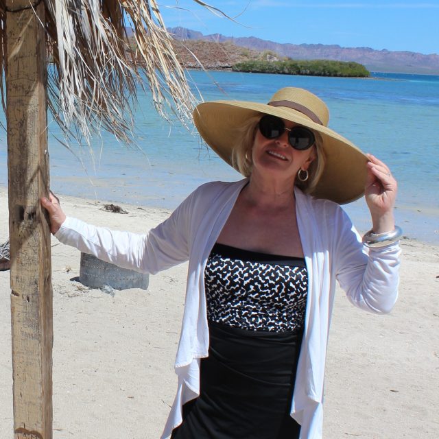 wearing a huge hat on a deserted beach