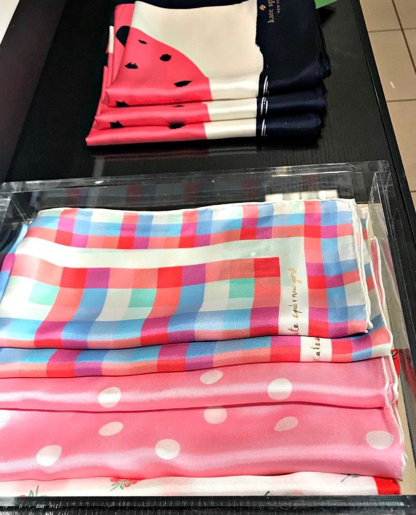 a tray of folded pink polka dot and plaid scarves