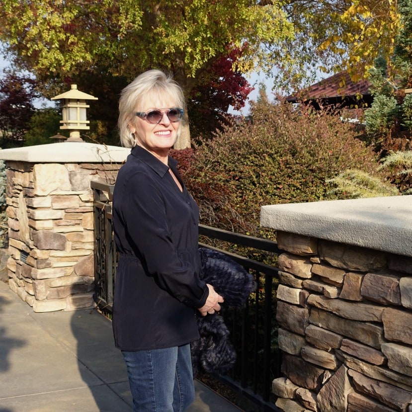 Jennifer Connolly wearing navy silk blouse and blue jeans with faux fur wrap