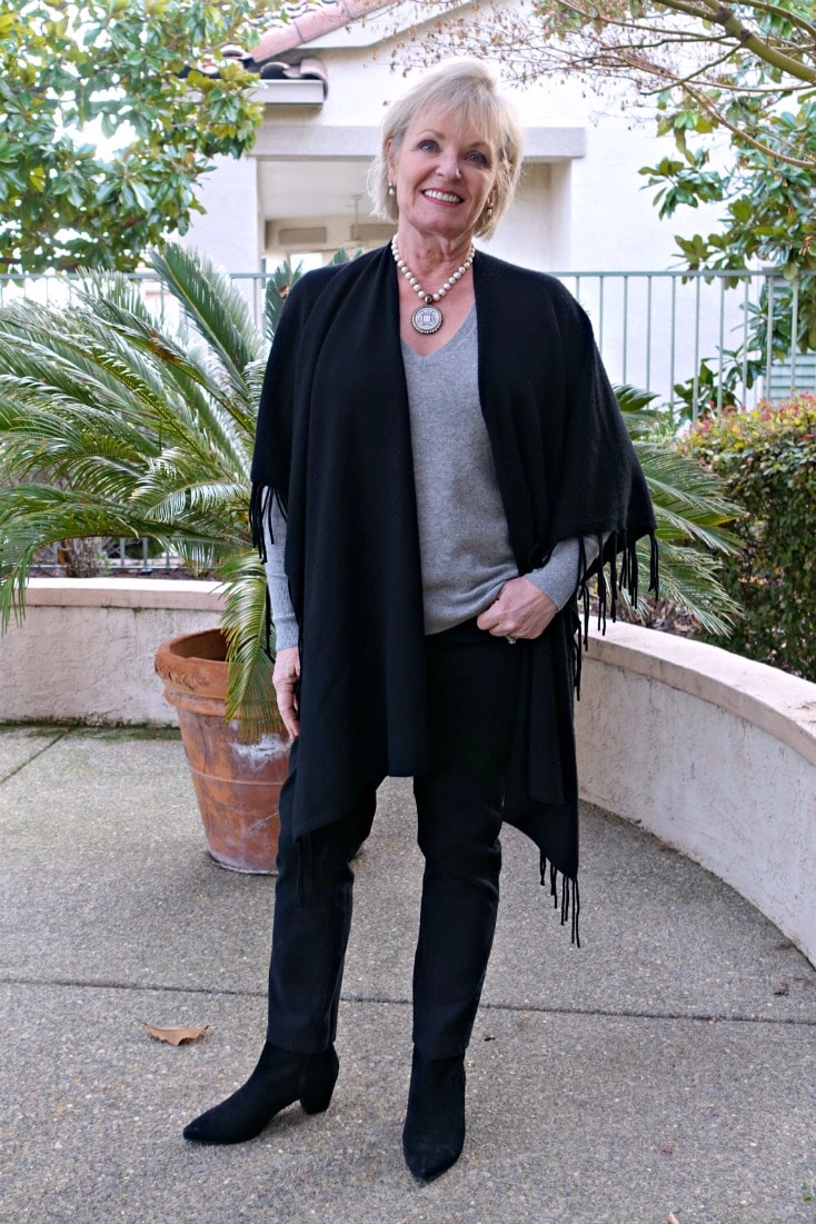 Jennifer Connolly wearing black ruana over gray sweater and black jeans