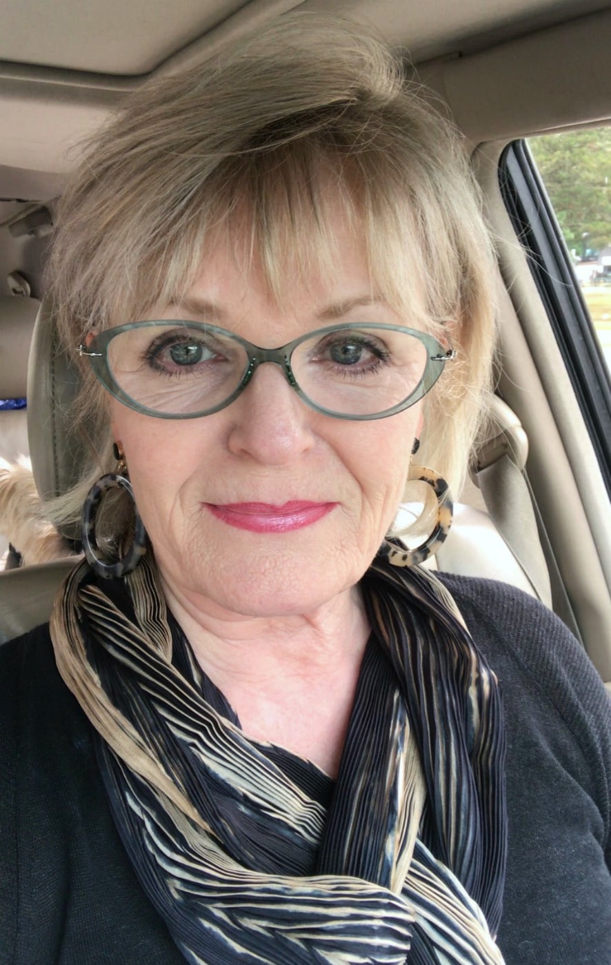 Jennifer Connolly of A Well Styled Life traveling in and RV we with beige and black scarf and Target earrings