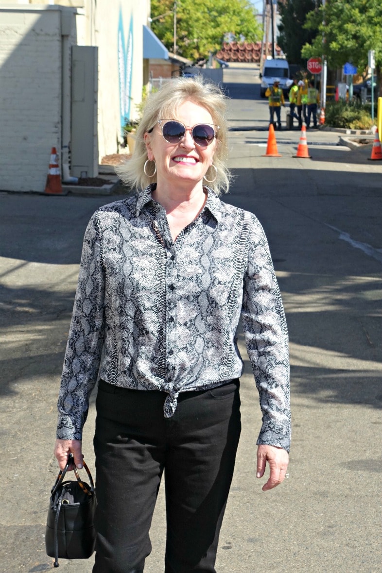 snakeskin print shirt ties at the waist over black jeans on Jennifer Connolly of A Well Styled Life