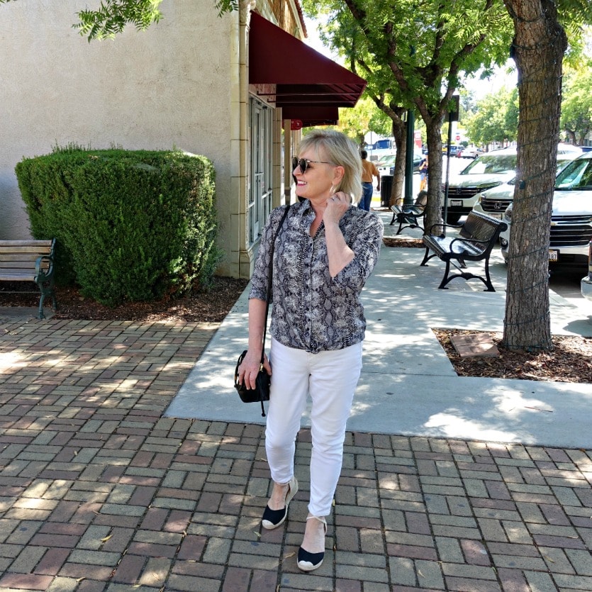 Jennifer Connolly of A Well Styled Life wearing casual white jeans and snakeskin print shirt on brick sidewalk