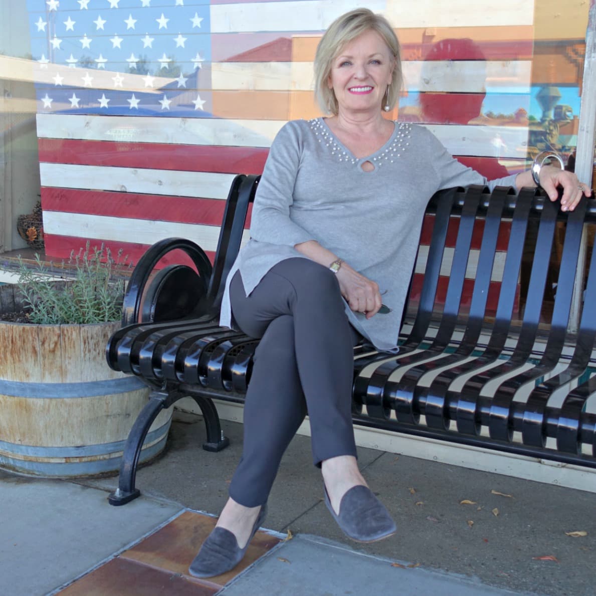 Jennifer Connolly of A Well Styled Life wearing gray tunic and gray leggings on bench in town