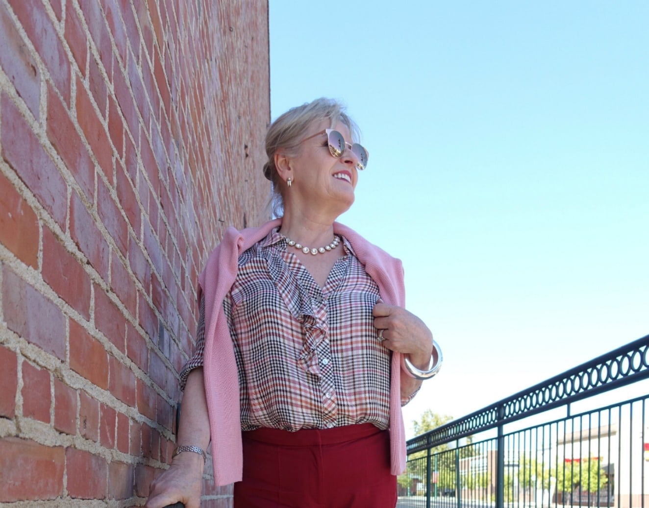 Jennifer Connolly of A Well Styled Life wearing causal plaid shirt with pink sweater over her shoulders