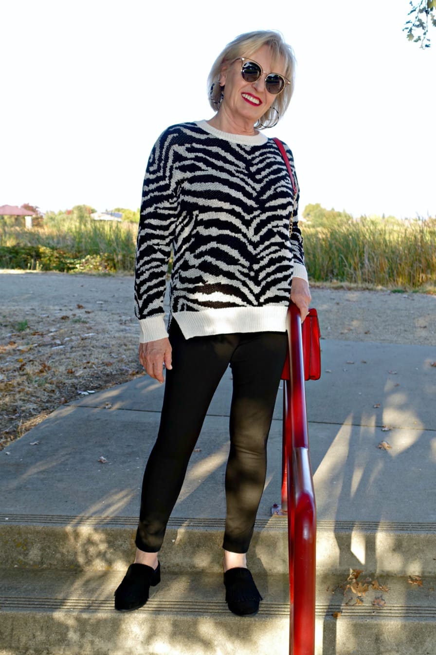 Jennifer Connolly of A Well Styled Life wearing black and white outfit with a tough of red