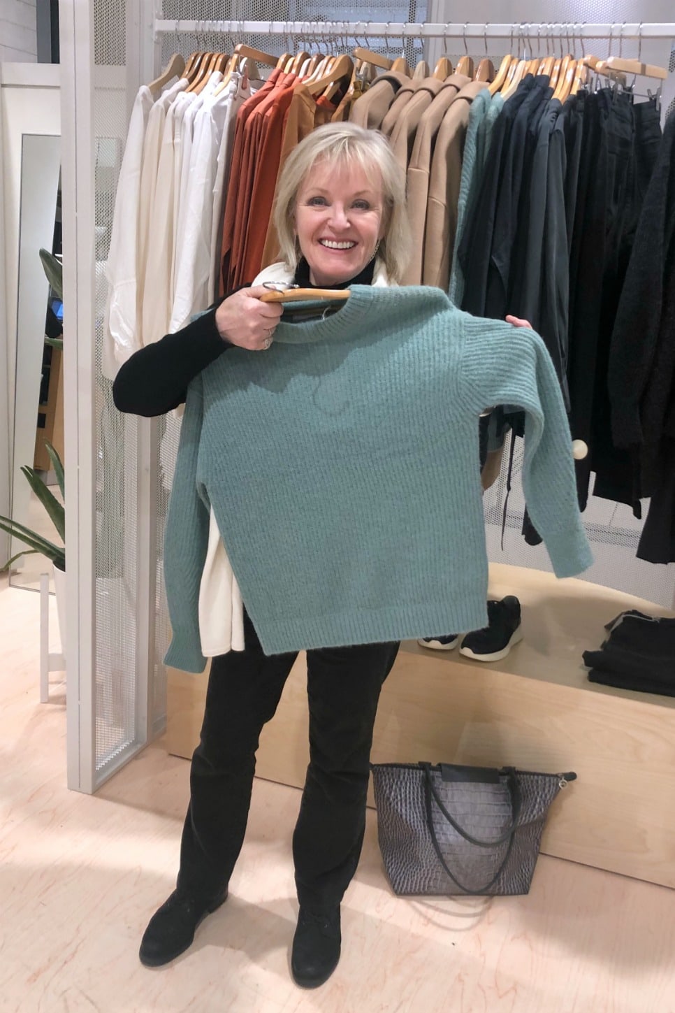 Jennifer Connolly holding green Everlane sweater in Nordstrom