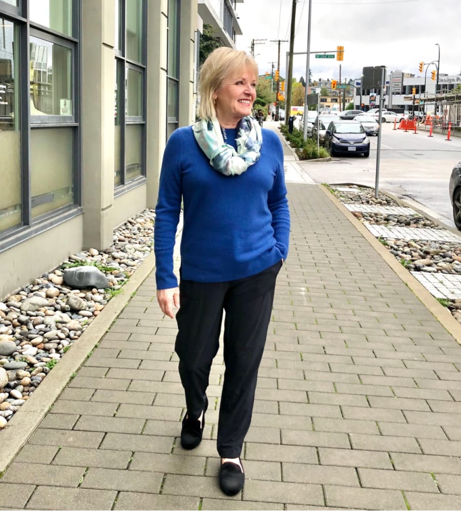 fashion blogger Jennifer of A well Styled Life walking down street in blue sweater, black pants and black shoes