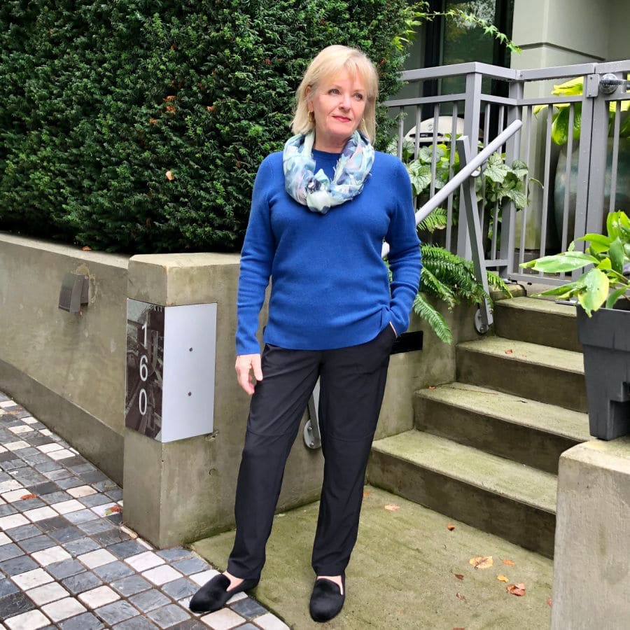 woman wearing scarf, blue sweater and black pants