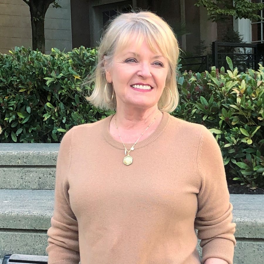 blonde woman wearing camel sweater and halogen jewelry