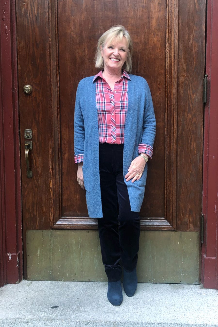 woman leaning against door wearing talbots sweater, shirt and boots