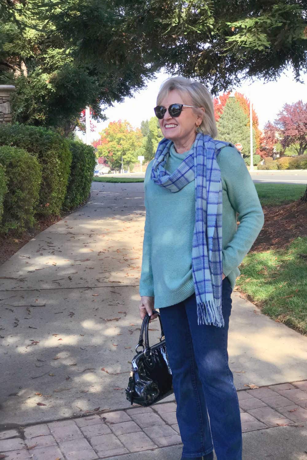 fashion blogger jennifer of a well styled life wearing plaid scarf over aqua sweater with blue jeans