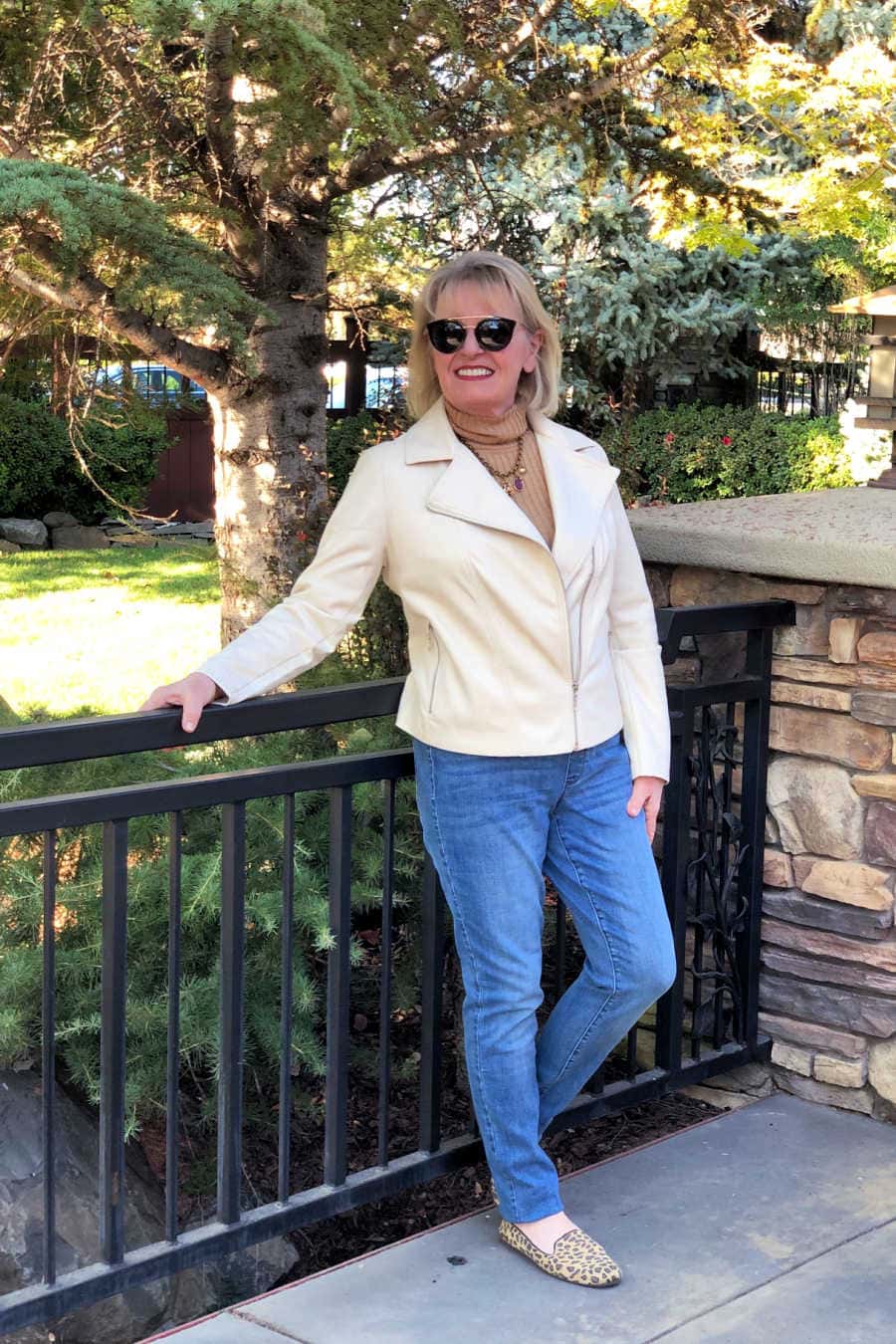 fashion blogger wearing faux leather jacket, blus jeans, leopard flats standing in front of all