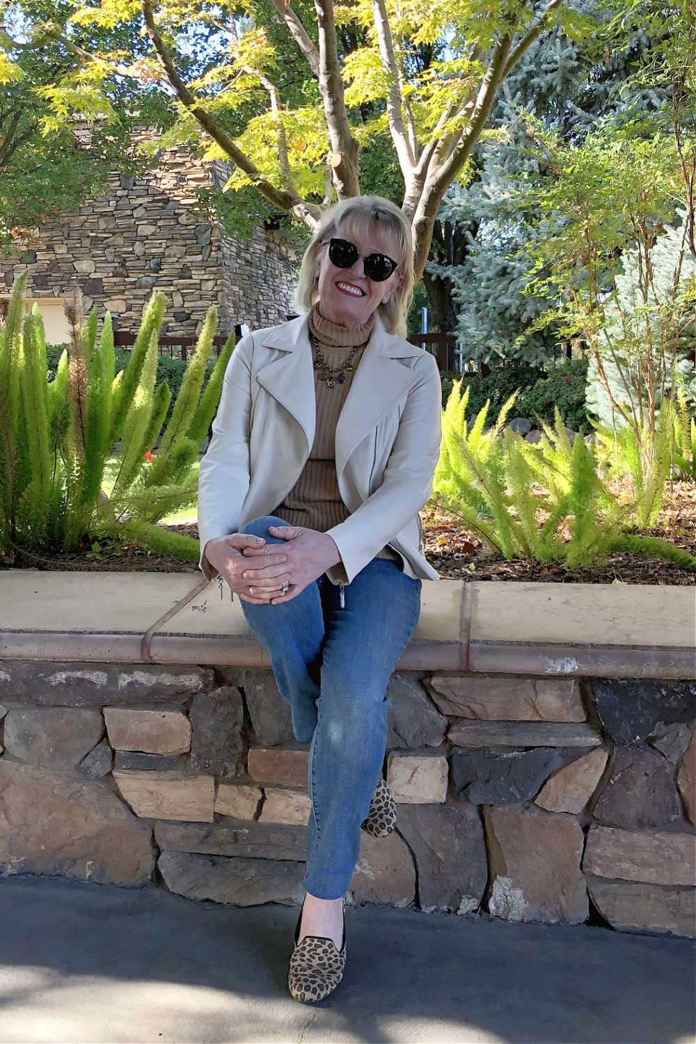 jennifer of a well styled life wearing ivory jacket, camel sweater and blue jeans
