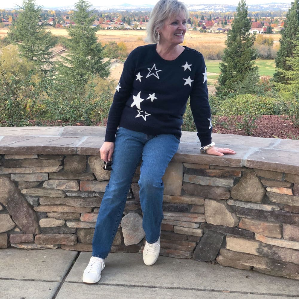 fashion blogger jennifer of a well styled life wearing navy halogen sweater and blue jeans sitting on wall