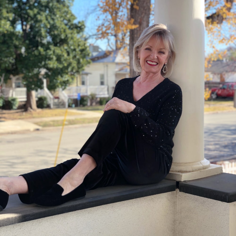fashion blogger jennifer connolly of a well styled life sitting on balcony wearing black outfit