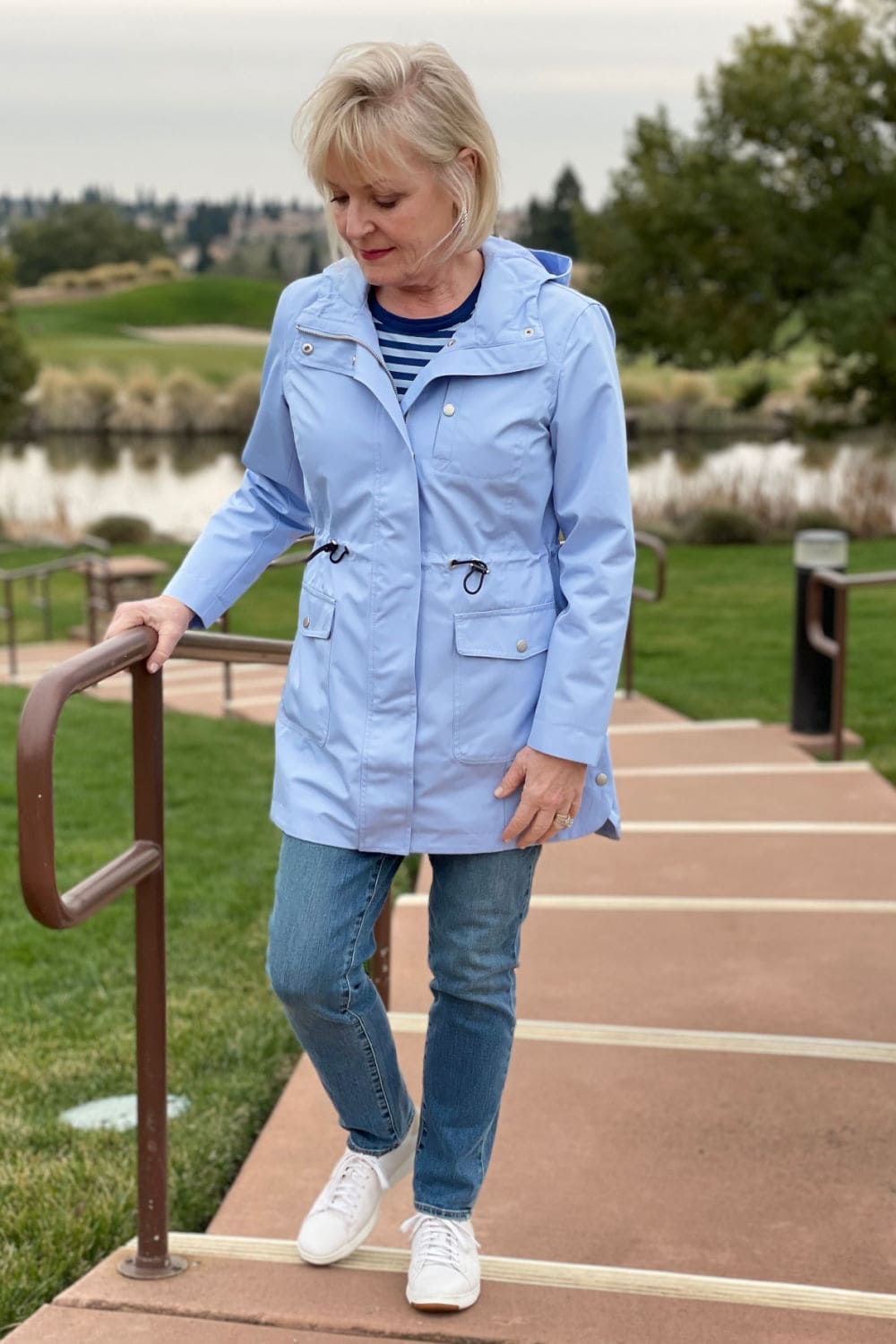 woman walking up the stairs in blue anorak and blue jeans
