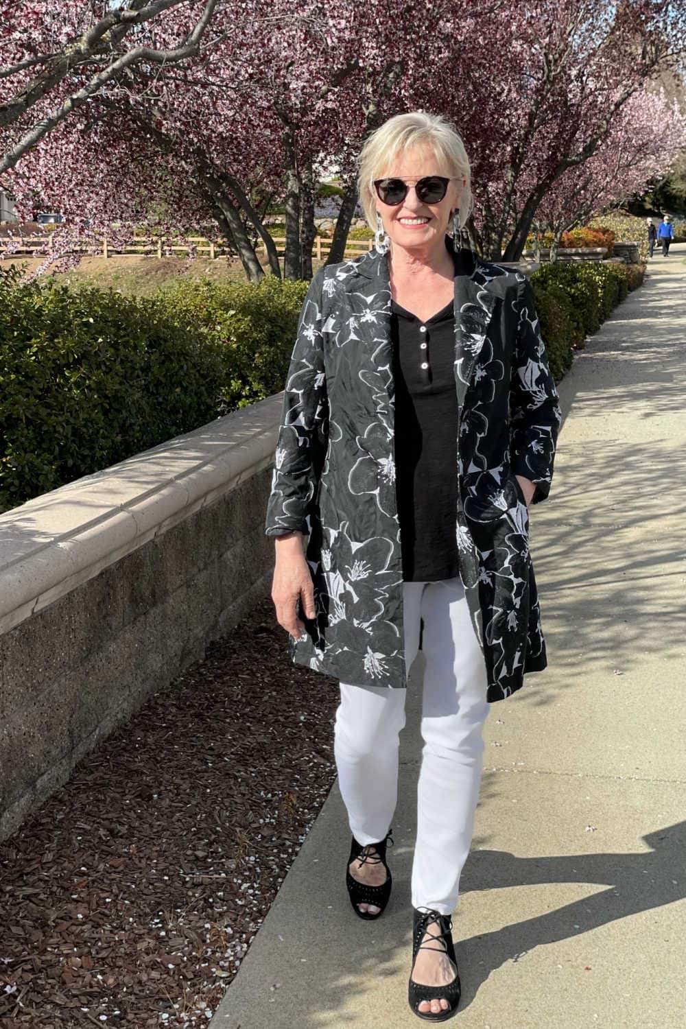 woman walking in white jeans and floral jacket