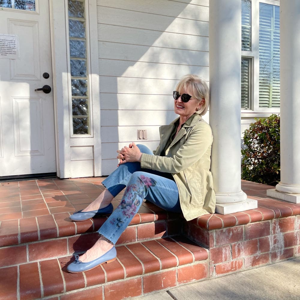 woman sitting on step of white building