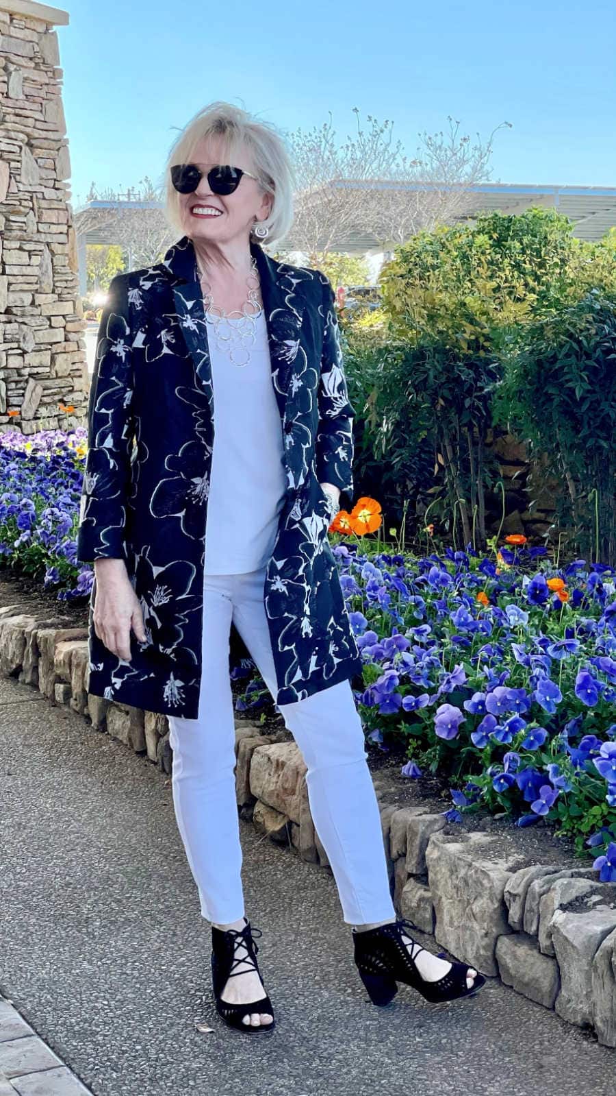 woman wearing a column of white under a floral blazer in black and white