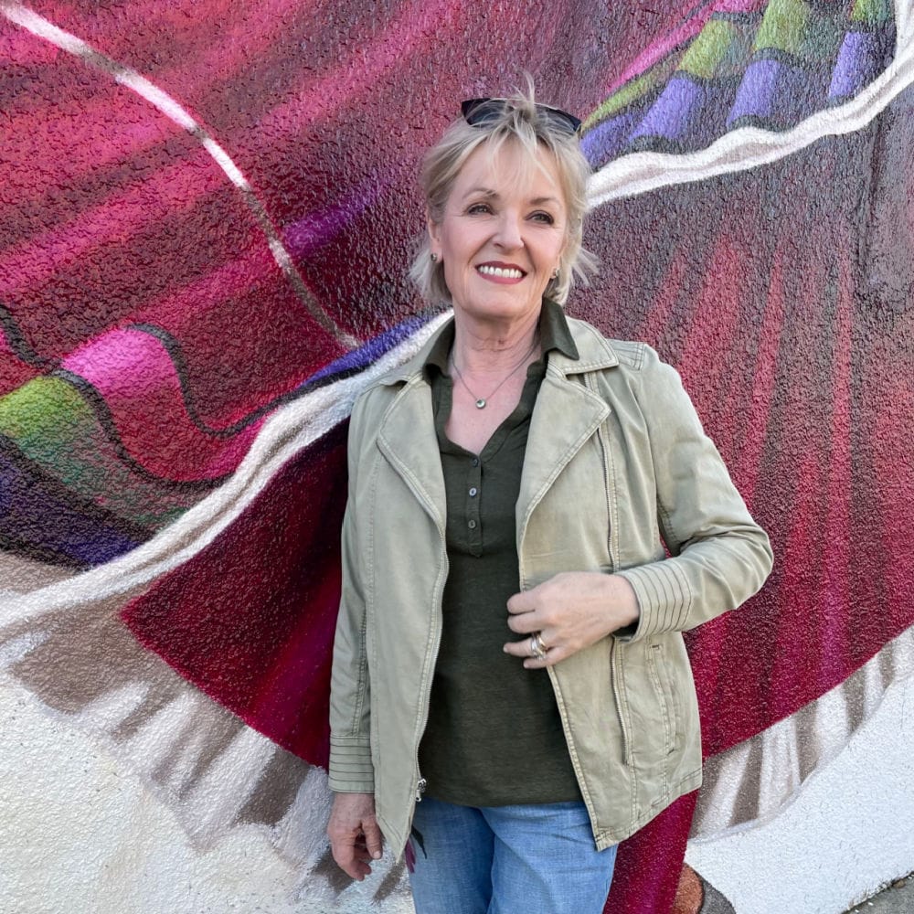 blonde woman wearing green jacket, green polo top and jeans