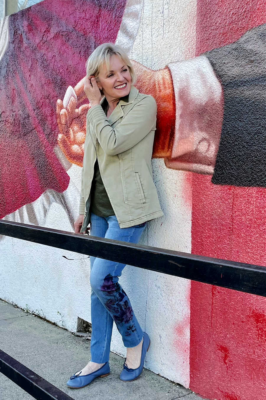 woman leaning against wall with mural of large hand