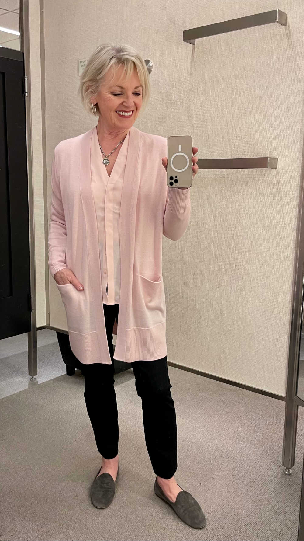woman in dressing room wearing pink sweater with black pants