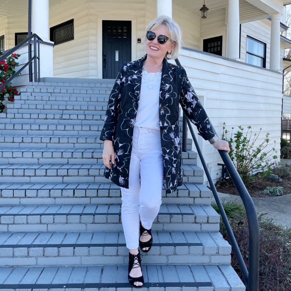 woman coming down stairs in white jeans with black and white jacket