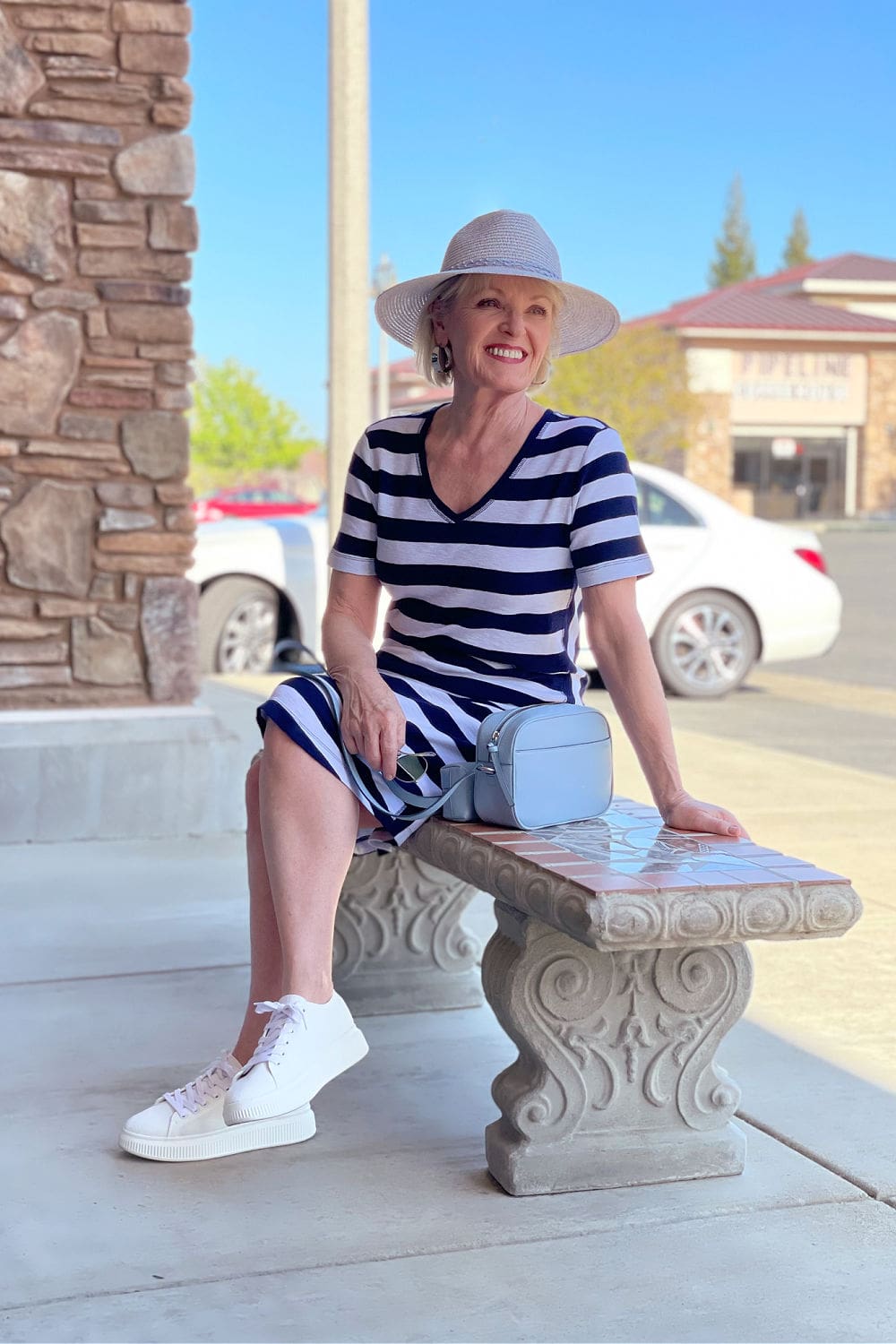 woman sitting on bench wearing white sneakers and athleisure striped tee dress