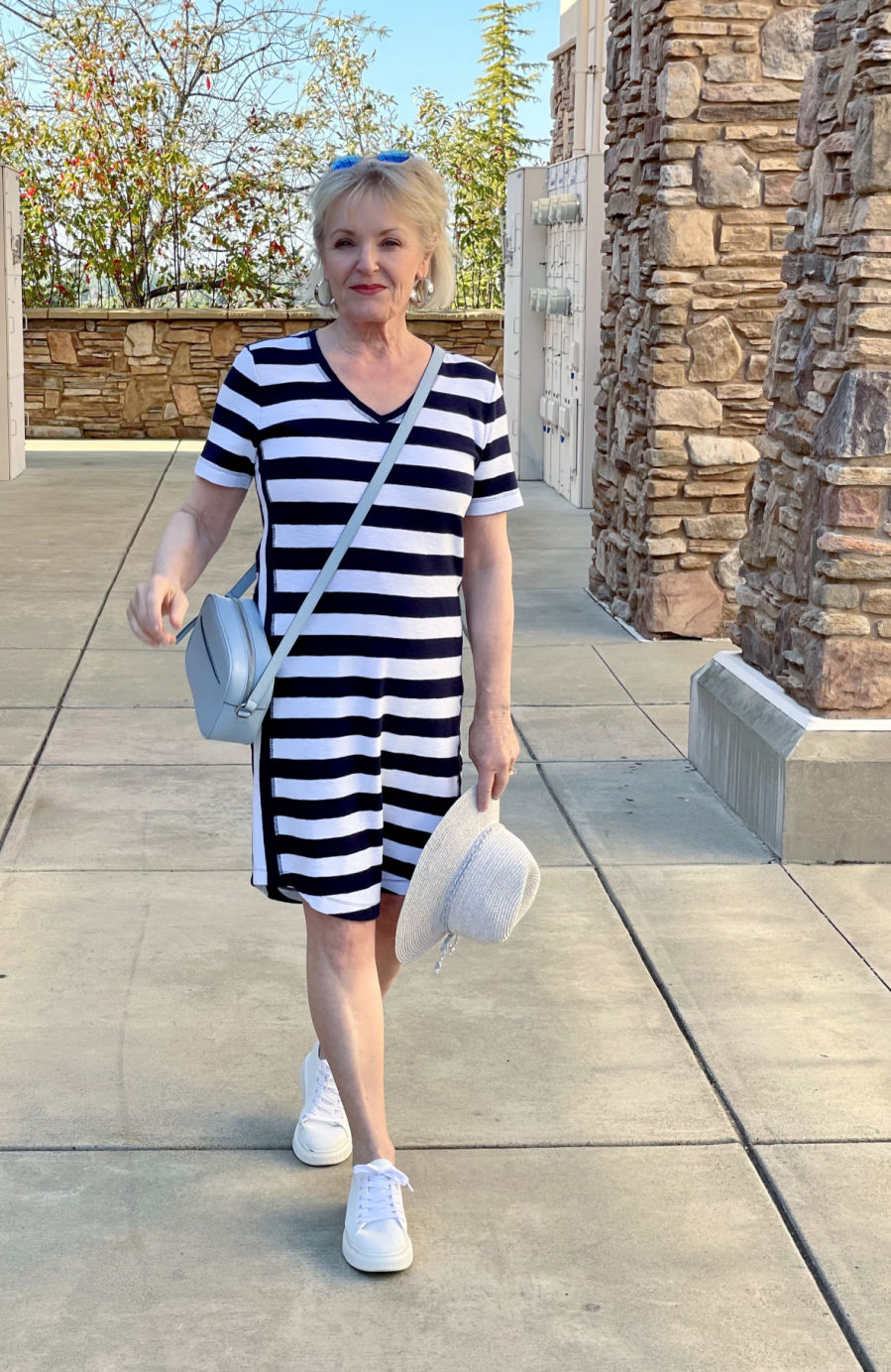 woman walking in navy and white striipe dress and white tennies