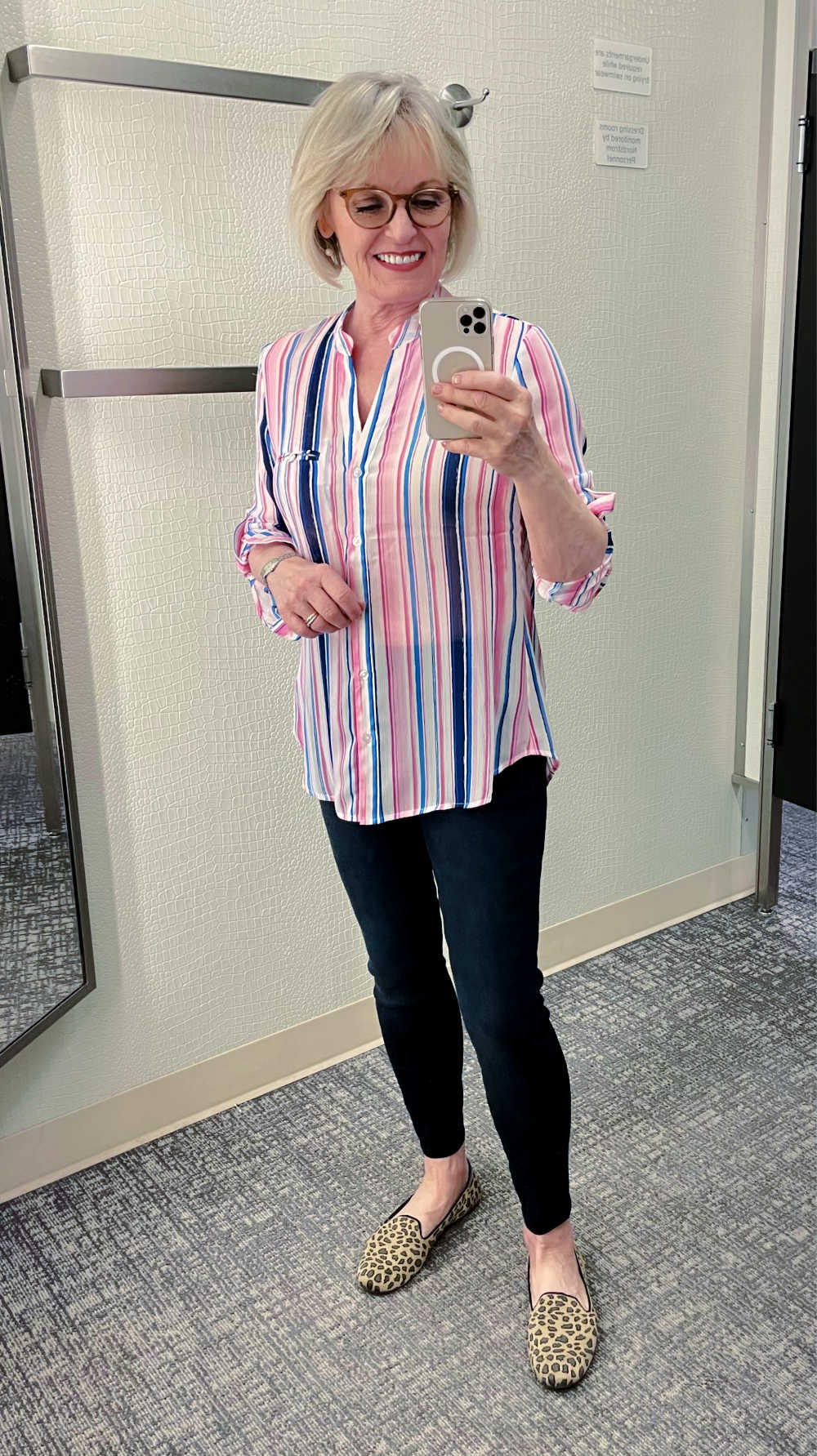 blonde womn taking selfie in mirror wearing striped shirt and dark denim