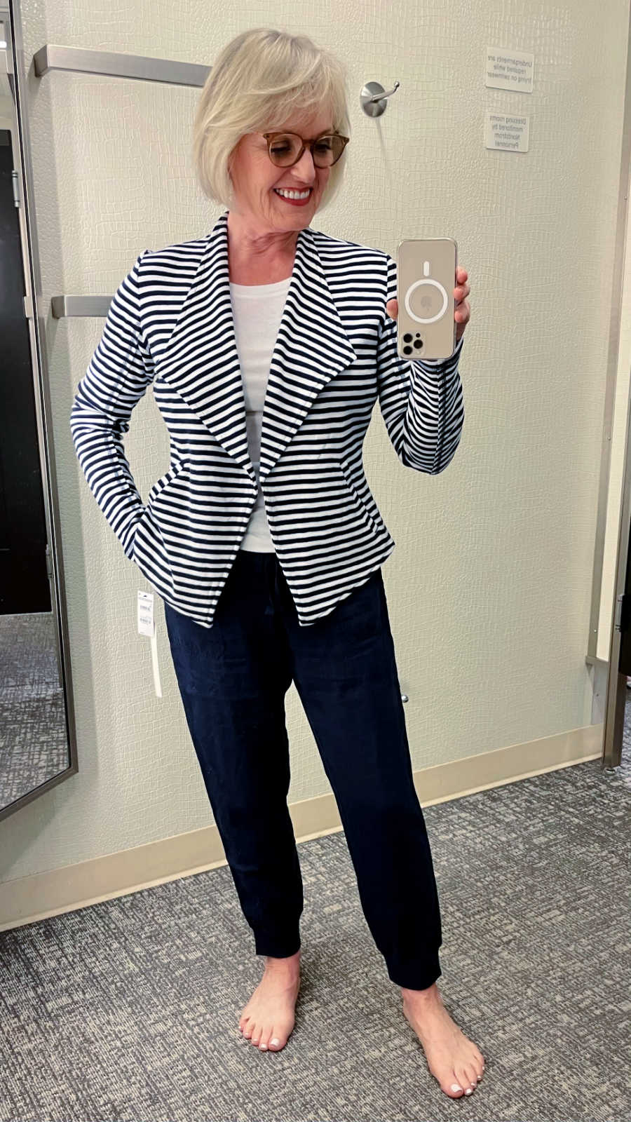 WOMAN TAKING SELFIE WEARING STRIPED JACKET AND NAVY LINEN PANTS