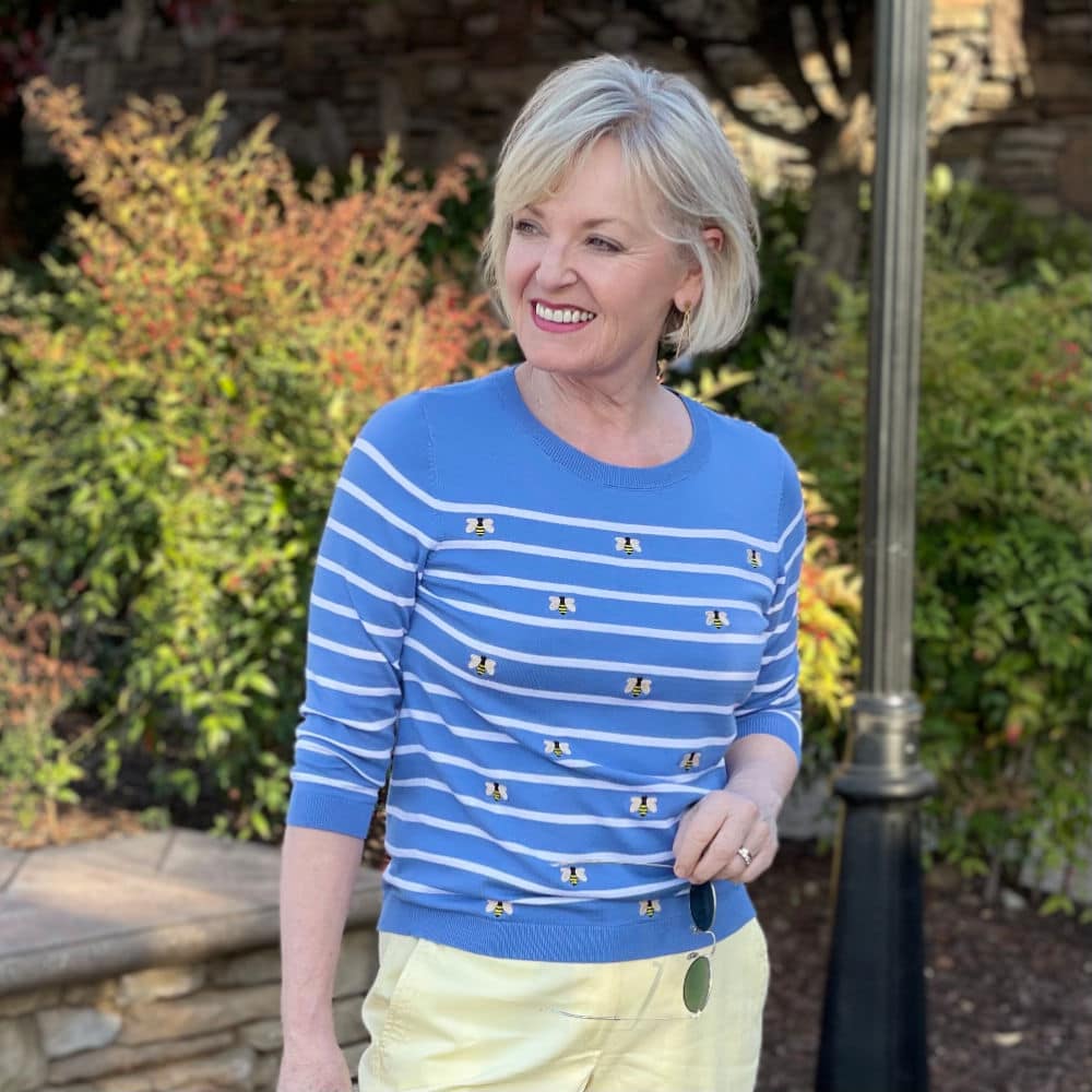 blonde woman wearing blue and white stripped sweater with bees on it