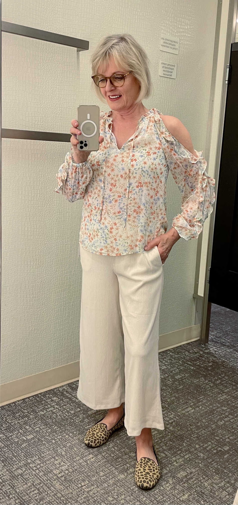 woman trying on crop pants and ruffle sleeve blouse in dressing room