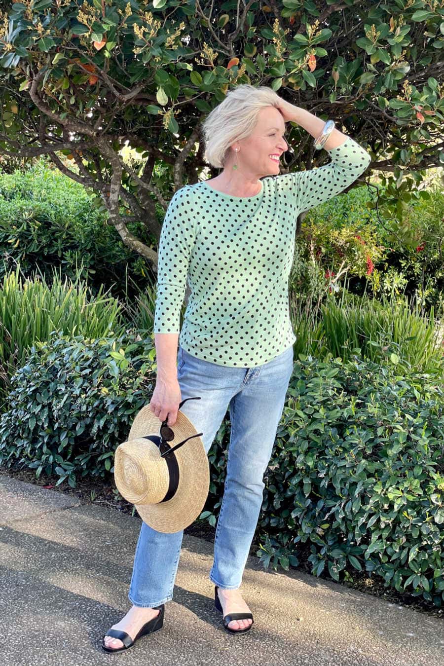 middle age woman wearing pale blue jeans and green polka dot sweater