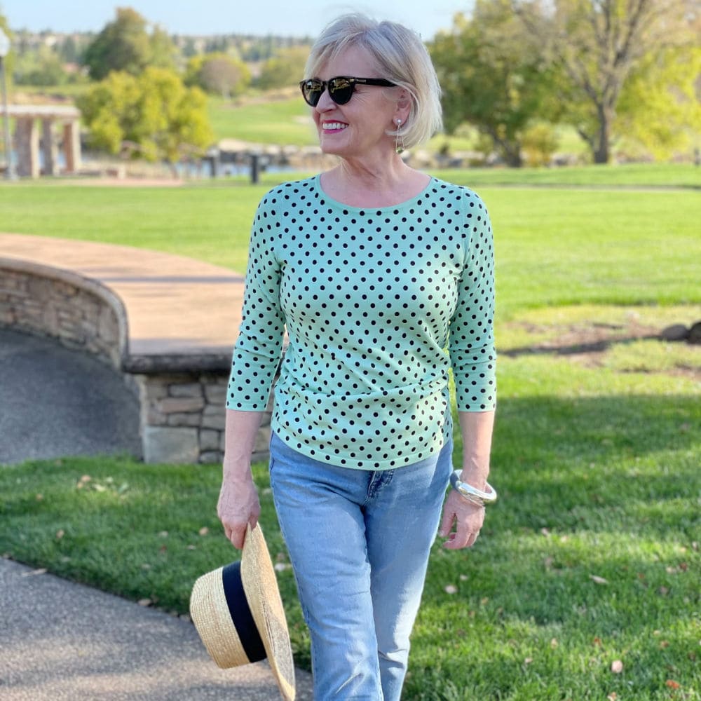 woman wearing green polka dot sweater and bue jeans